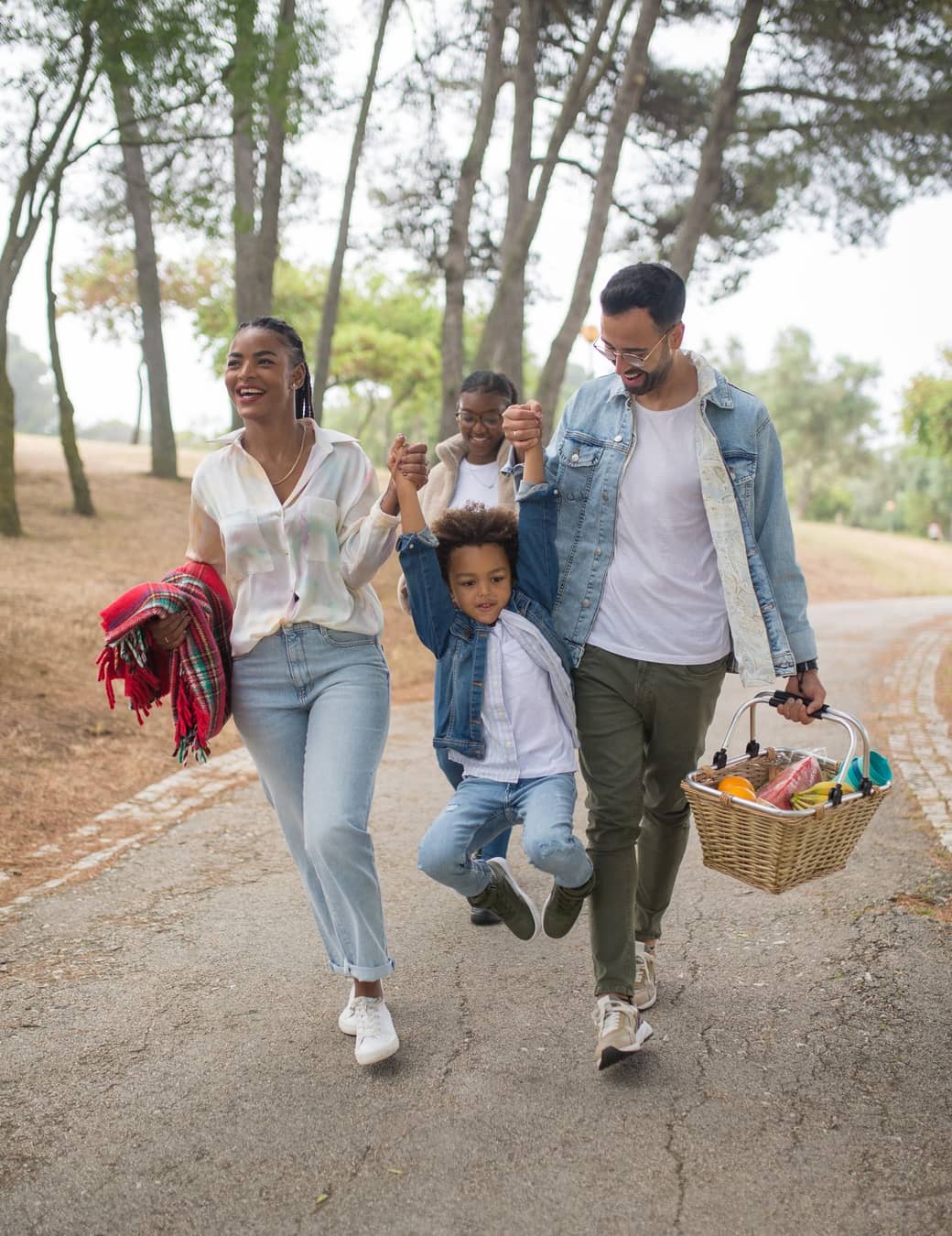 Família caminhando junta em um parque, com as crianças brincando pelo caminho